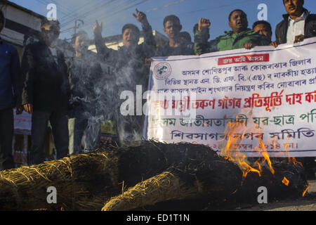 Sivasagar, Assam, Indien. 24. Dezember 2014. Indien, SIVASAGAR: Aktivisten der Asom Jatiyatabadi Yuba Charta Parishad (AJYCP) brennen das Bildnis von Assam Ministerpräsident Tarun Gogoi aus Protest gegen Angriffe auf die Dorfbewohner von militanten an vier verschiedenen Orten im Sivasagar Viertel der nordöstliche Assam Zustand am 24. Dezember 2014. Stockfoto