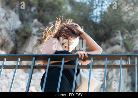 Frau sieht über die Reling an windigen Tag Stockfoto