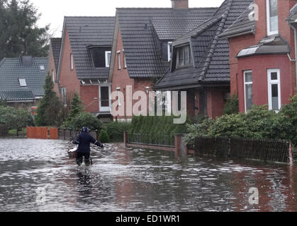Kellinghusen, Deutschland. 24. Dezember 2014. Anwohner waten durch eine überschwemmte Straße in Kellinghusen, Deutschland, 24. Dezember 2014. Dauerregen in Norddeutschland hat Flüsse zu brechen ihre Banken und Überschwemmungen in mehreren Bereichen verursacht. Foto: DANIEL FRIEDERICHS/Dpa/Alamy Live News Stockfoto