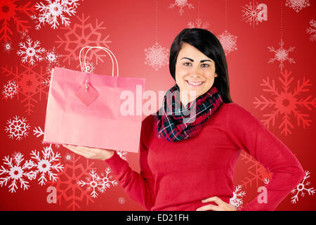 Lächelnde Brünette zeigt rote Geschenktüte Stockfoto