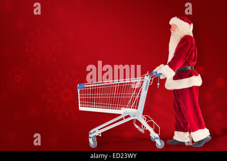 Zusammengesetztes Bild von Santa schiebt einen Einkaufswagen Stockfoto