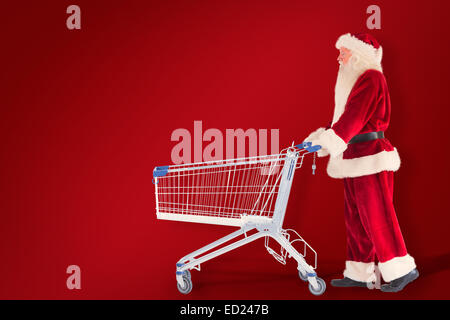 Zusammengesetztes Bild von Santa schiebt einen Einkaufswagen Stockfoto