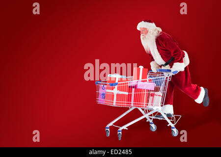 Zusammengesetztes Bild von Santa schiebt einen Einkaufswagen Stockfoto