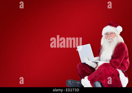 Zusammengesetztes Bild von Santa sitzt und einen laptop Stockfoto