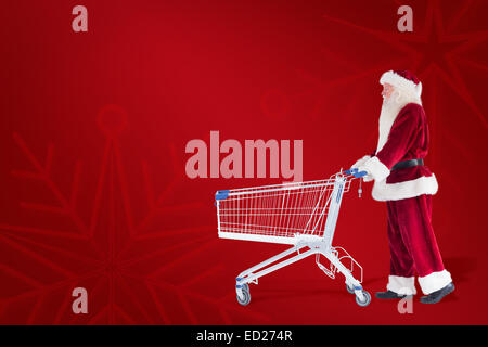 Zusammengesetztes Bild von Santa schiebt einen Einkaufswagen Stockfoto
