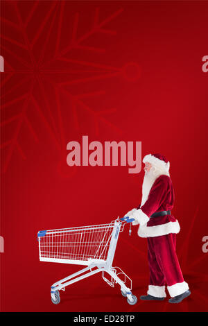 Zusammengesetztes Bild von Santa schiebt einen Einkaufswagen Stockfoto