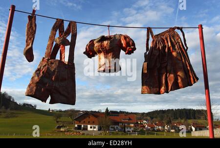 Maierhoefen, Deutschland. 22. Dezember 2014. Bayerische Trachten hergestellt aus Kunststoff hängen von einer Wäscheleine in Maierhoefen, Deutschland, 22. Dezember 2014. Die ursprünglich leuchtend rot Kunstinstallation von Künstlerin Norma Sperling-Osterkorn, die jetzt durch das Wetter verblasst ist, ist Bestandteil Maierhoefens "Skulpturenweg" von lokalen Künstlern gestaltet. Foto: Karl-Josef Hildenbrand/Dpa/Alamy Live News Stockfoto