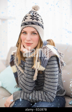 Zusammengesetztes Bild süße Blondine im Winter Hut sitzt auf der Couch posiert Stockfoto