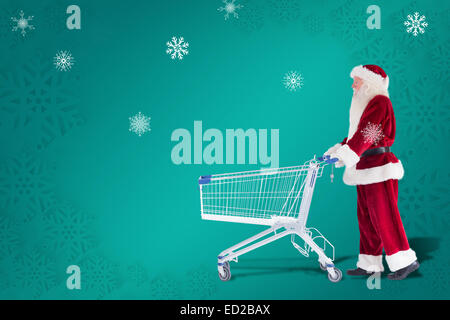 Zusammengesetztes Bild von Santa schiebt einen Einkaufswagen Stockfoto
