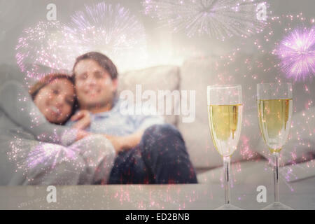 Zusammengesetztes Bild des Paares ruht auf einer Couch mit Kanneluren Champagner Stockfoto