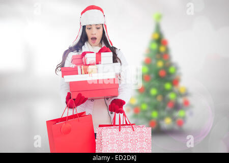 Zusammengesetztes Bild überrascht Brünette in Winterkleidung hält viele Geschenke und Einkaufstaschen Stockfoto