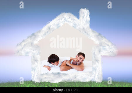 Zusammengesetztes Bild von Vater und Sohn Spaß auf einem Bett Stockfoto