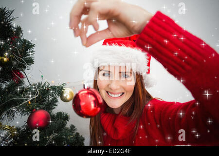 Zusammengesetztes Bild von festlichen Redhead Christbaumkugel am Baum hängen Stockfoto