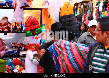 La Paz, Bolivien, 24. Dezember 2014. Ein Aymara-Frau oder Cholita tragen traditionelle Kleidung tut ihre Weihnachtseinkäufe an einem Straßenstand in einen Weihnachtsmarkt. Bildnachweis: James Brunker / Alamy Live News Stockfoto