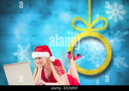 Zusammengesetztes Bild der festlichen Blondine mit einem laptop Stockfoto