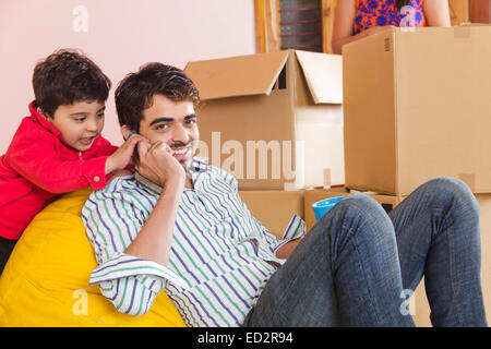 indische Eltern und Sohn nach Hause sprechendes Telefon Stockfoto