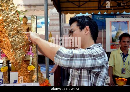 NAKHON PATHOM, THAILAND: Junger Mann gilt ein Stück Blattgold Applikation für eine Buddhafigur Stockfoto