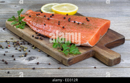 Nahaufnahme von köstlich frisches Lachsfilet; vorne, mit Kräutern, Gewürzen und Zitronenscheiben auf rustikalen Holz im Fokus Stockfoto