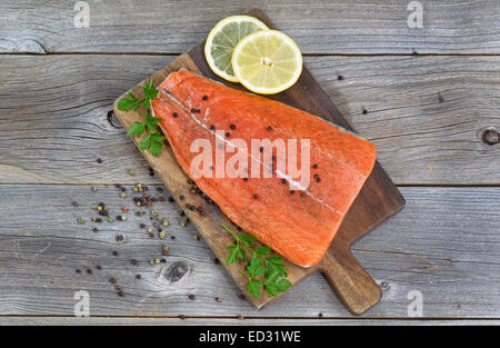 Ansicht von oben Bild ein frisches Lachsfilet mit Kräutern, Gewürzen und Zitronenscheiben auf rustikalen Holz fertig gekocht werden. Stockfoto