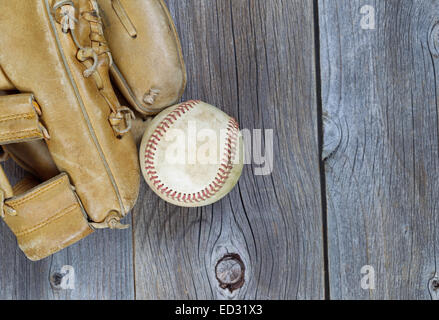 Teilweise alte abgenutzte Handschuh und gebrauchte Baseball auf rustikalen Holz Stockfoto