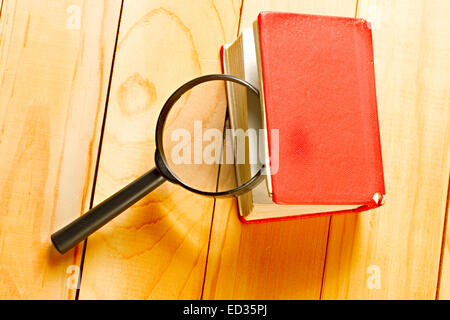 Lupe und Buch auf dem hölzernen Hintergrund Stockfoto