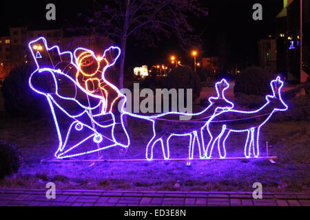 violette Lichtinstallation Weihnachtsmann im Schlitten mit Hirschen fahren am Abend Straße Stockfoto