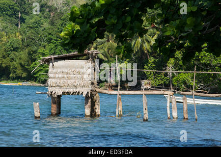 Melanesien, Papua Neu Guinea, Dobutamin Insel. Typische Inseldorf über Wasser Nebengebäude, junges Mädchen auf dem Gehweg. Stockfoto