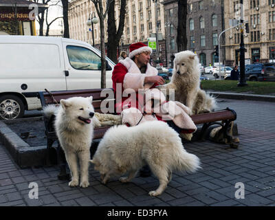 Kiew, Ukraine. 25. Dezember 2014. In Donnerstag, 25. Dezember 2014 sitzt auf Khreschatyk Street, Kiew, Ukraine, einen jungen Mann mit weißen flauschigen Hunde als Weihnachtsmann verkleidet. Bildnachweis: Igor Golovnov/Alamy Live-Nachrichten Stockfoto