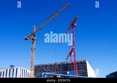 Baustelle mit orangefarbenen und roten Kränen und blauen Sommerhimmel Stockfoto