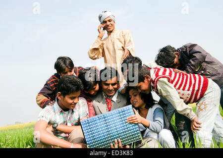 indische ländlichen Bauernfamilie mit Geschäftsmann Laptop arbeiten Stockfoto