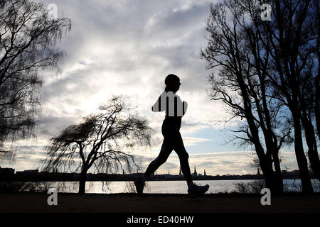 Hamburg, Deutschland. 26. Dezember 2014. Ein Jogger verläuft entlang der Alster in Hamburg, Germany, 26. Dezember 2014. Nach einigen Tagen mit heftigem Regen in der Hansestadt ist die Sonne auf den zweiten Weihnachtsfeiertag. Foto: MALTE Christen/Dpa/Alamy Live News Stockfoto