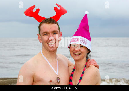 Prestwick, Schottland, Vereinigtes Königreich. 26. Dezember 2014. Die 9. jährliche Clic Sergent Weihnachtstag schwimmen tagte in Prestwick Strand, Ayrshire, in der Nähe des Hospizes. Dies zog über 200 Schwimmer, die viele in Fancy Dress Kostüme zum Strand von lokalen Piper Billy Kenny marschiert waren. Dieses Jahr war besonders kostspielig für Clicsergent, als während der jüngsten stürmen das Hospiz zweimal durch Blitzschlag verursacht mehr als £200.000 Wert von Schäden und Störungen zu kümmern getroffen wurde. Die Schwimmer hoffen, mehr als £25.000 durch Sponsoring zu erheben. Bildnachweis: Findlay/Alamy Live-Nachrichten Stockfoto