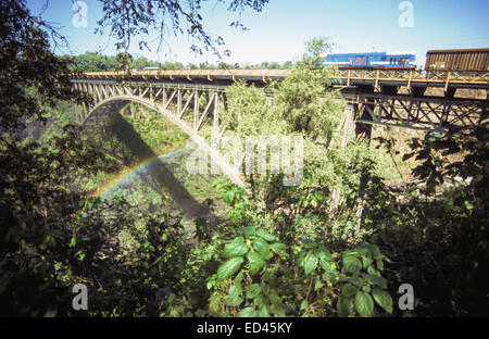 Zug über die Brücke über den Sambesi-Fluss auf der Zimbabwe-Zambia Grenze mit einem Regenbogen, Viktoriafälle, Simbabwe Stockfoto