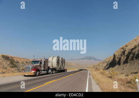 Eine amerikanische Peterbilt 379 Semi Truck schleppen Rollen von HDPE-Kunststoff Rohr auf einem Tieflader für die Ölindustrie und fracking Standorten in den USA Stockfoto