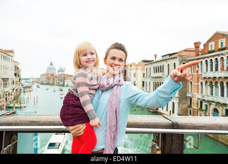 Baby Mädchen und Mutter deutete beim stehen auf der Brücke mit Blick auf Canale Grande in Venedig, Italien Stockfoto