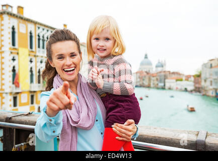 Baby Mädchen und Mutter deutete in der Kamera beim stehen auf der Brücke mit Blick auf Canale Grande in Venedig, Italien Stockfoto