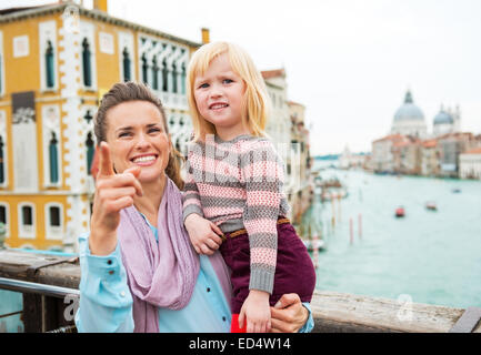 Baby Mädchen und Mutter deutete beim stehen auf der Brücke mit Blick auf Canale Grande in Venedig, Italien Stockfoto