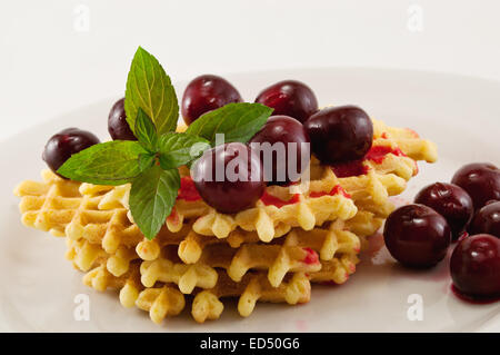 Waffeln mit frischen Kirschen und Minze auf einem weißen Teller Stockfoto