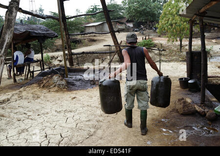 EXKLUSIV - BOJONEGORO, INDONESIEN. 13. November 2014 - trägt ein Arbeitnehmer Container von Rohöl zu Benzin im Subd verarbeitet werden Stockfoto