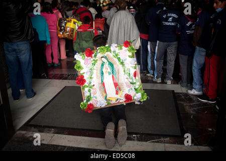 Ein Mann geht auf die Knie tragen ein Bild der Jungfrau von Guadalupe, dekoriert mit Blumen in Mexiko Stockfoto