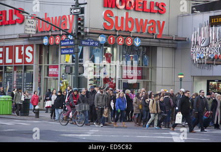 Menschenmassen Kreuz 34th St. an der Seventh Avenue während der Ferienzeit in Manhattan, NYC. Stockfoto