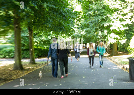 Menschen, die ein Spaziergang durch einen Park an einem Sommertag. Verschwommen in Teilen. Stockfoto