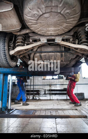 in einer Garage - zwei Mechaniker arbeitet an einem Auto Radwechsel, Wartungsarbeiten (flachen DOF; getönten Farbbild) Stockfoto