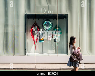 Frau, die an einem Dior-Schaufenster in der Omotesando-Straße vorbeikommt Stockfoto