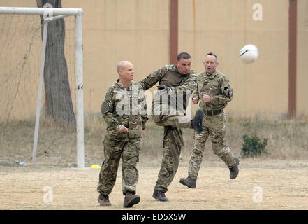 Kabul, Afghanistan. 24. Dezember 2014. Britische und deutsche Soldaten kämpfen um den Ball bei einem Fußballspiel auf der umgestalteten Heliport des ISAF-Hauptquartiers in Kabul, Afghanistan, 24. Dezember 2014. Anlässlich des 100. Jahrestages der "Christmas Truce" bei deutschen, britischen und französischen Soldaten ihre Waffen in den Schützengräben Flanderns in 1914 einige Fußball spielen initiiert die deutschen und britischen Soldaten in Kabul das Spiel. Foto: Subel Bhandari/Dpa/Alamy Live News Stockfoto