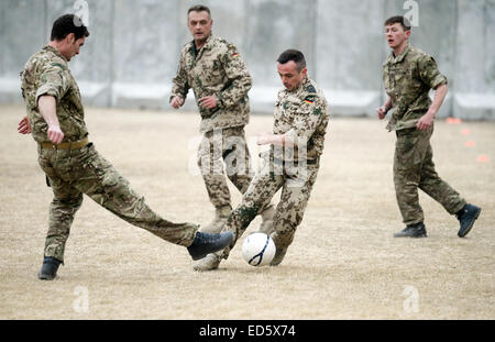 Kabul, Afghanistan. 24. Dezember 2014. Britische und deutsche Soldaten kämpfen um den Ball bei einem Fußballspiel auf der umgestalteten Heliport des ISAF-Hauptquartiers in Kabul, Afghanistan, 24. Dezember 2014. Anlässlich des 100. Jahrestages der "Christmas Truce" bei deutschen, britischen und französischen Soldaten ihre Waffen in den Schützengräben Flanderns in 1914 einige Fußball spielen initiiert die deutschen und britischen Soldaten in Kabul das Spiel. Foto: Subel Bhandari/Dpa/Alamy Live News Stockfoto