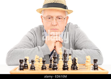 Senior über seinen nächsten Schritt im Schachspiel isoliert auf weißem Hintergrund Stockfoto