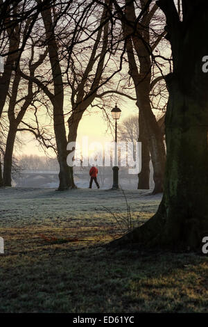 Mann im roten Mantel zu Fuß durch den Avenham Park in Preston, Lancashire Stockfoto