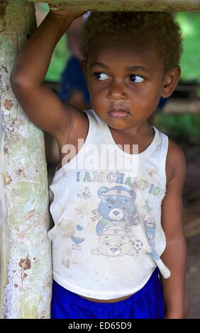 PENTECOSTES, VANUATU-Oktober 15, 2014: Kleiner Junge begleitet ihre Mutter, die Frucht in einem Stall in der Nähe des Flughafens am 1. Oktober verkauft Stockfoto