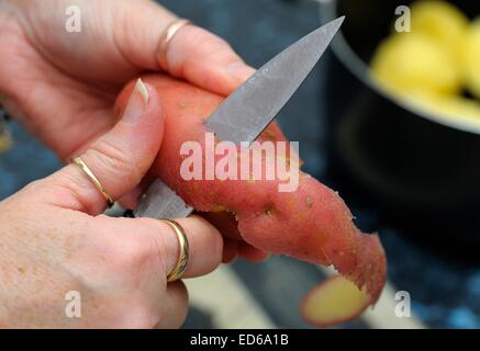 Rote Kartoffeln geschält wird von hand mit Messer in einer britischen Küche. Stockfoto